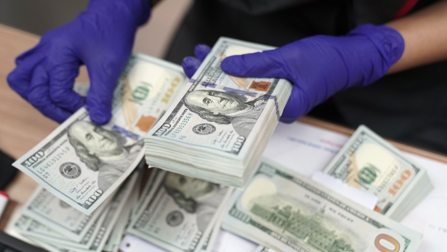 Seorang karyawan yang mengenakan sarung tangan pelindung menghitung uang kertas dolar AS di penukaran mata uang (Dimas Ardian/Bloomberg)