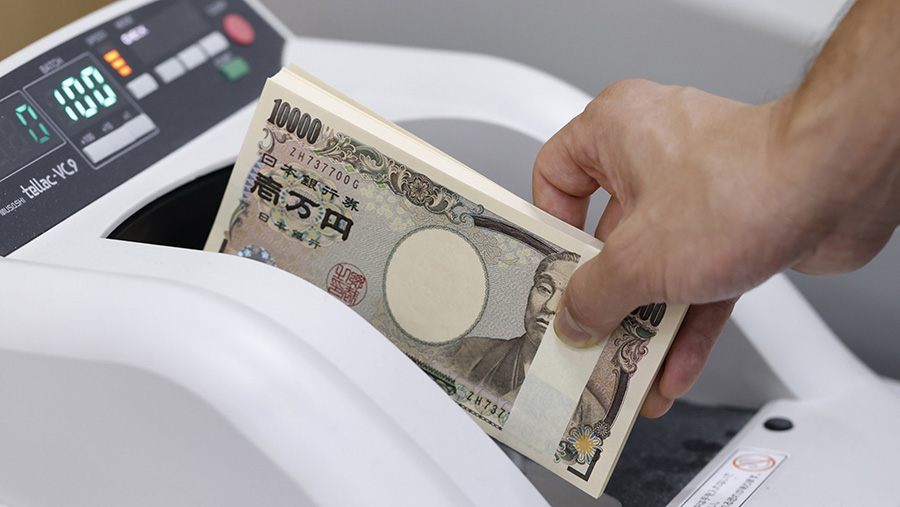 Seorang karyawan menempatkan uang kertas 10.000 yen Jepang di mesin penghitung mata uang Resona Bank Ltd. di Tokyo, Jepang. (Kiyoshi Ota/Bloomberg)