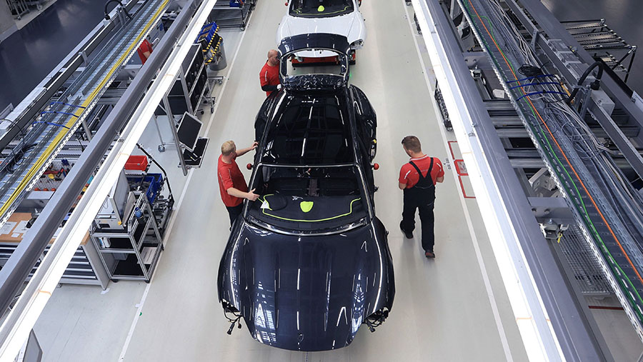 Para karyawan mengerjakan kerangka bodi mobil Porsche Taycan di lini produksi di pabrik Porsche AG di Stuttgart, Jerman. (Krisztian Bocsi/Bloomberg)