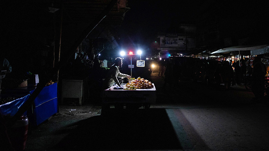 Pedagang menjual buah di bawah lampu baterai akibat pemadaman listrik di Lahore, Pakistan, Senin (23/1/2023). (Betsy Joles/Bloomberg)