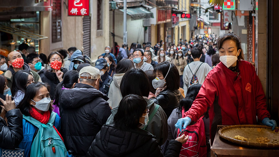 Seorang penjual menawarkan sampel kue almond kepada pengunjung di St. Paul's Street, Makau, China, Rabu (25/1/2023). (Eduardo Leal/Bloomberg)