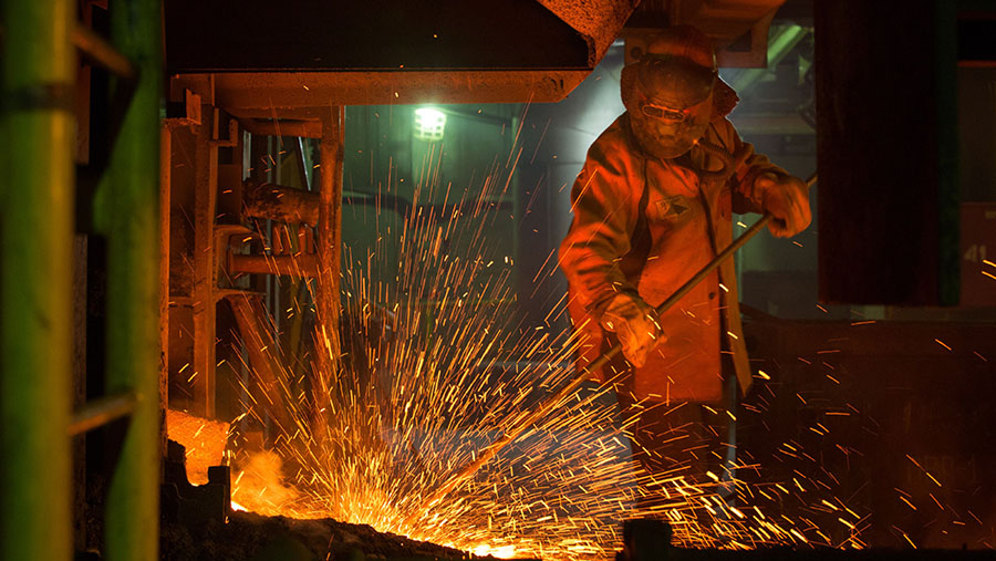 Pekerja mengawasi aliran logam cair panas hasil tambang nikel saat mengalir dari tungku di Norilsk, Rusia. (Andrey Rudakov/Bloomberg)