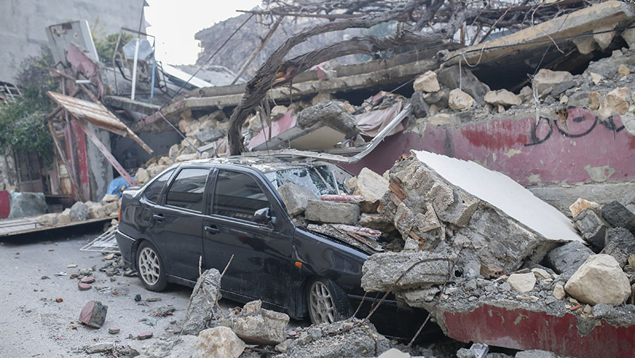 Puing-puing dari bangunan yang hancur akibat gempa menutupi sebuah mobil di jalan di Hatay, Turki, Rabu (8/2/2023). (Cansu Yildirann/Bloomberg)