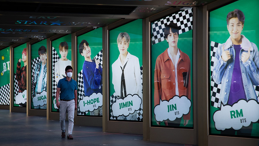 Seorang pejalan kaki berjalan melewati iklan boy band K-pop BTS yang ditampilkan di Seoul, Korea Selatan, Jumat (18/9/2020). (SeongJoon Cho/Bloomberg)