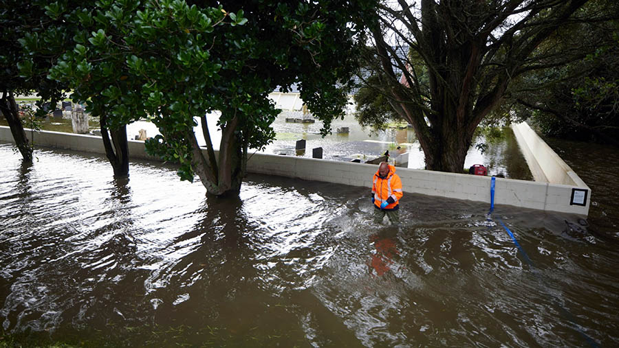 Seorang pekerja berjalan di air banjir setelah Topan Gabrielle di Auckland, Selandia Baru, Selasa (14/2/2023). (Brendon O'Hagan/Bloomberg)