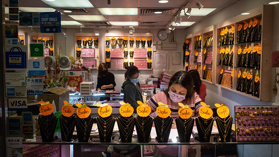 Penjual dengan mengunakan masker beraktivtas di dalam toko aksesoris di Hong Kong, Rabu (1/3/2023). (Billy H.C. Kwok/Bloomberg)