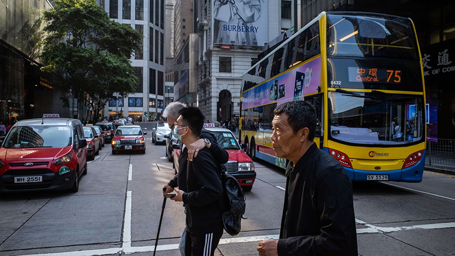 Pejalan kaki menyeberang jalan di Hong Kong, Rabu (1/3/2023). (Billy H.C. Kwok/Bloomberg)