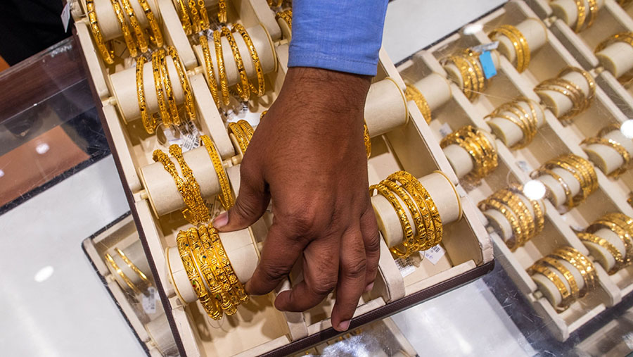 Seorang karyawan memajang gelang emas di dalam toko Kalyan Jewellers di Noida, India. (Prashanth Vishwanathan/Bloomberg)