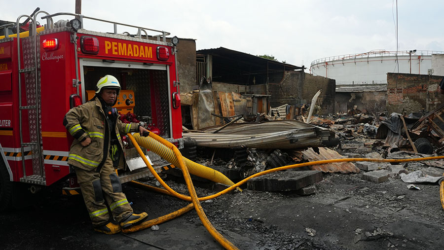 Petugas pemadam di pemukiman warga yang terbakar usai kebakaran di depo Pertamina Plumpang, Jakarta, Sabtu (4/3/2023). (Dimas Ardian/Bloomberg)