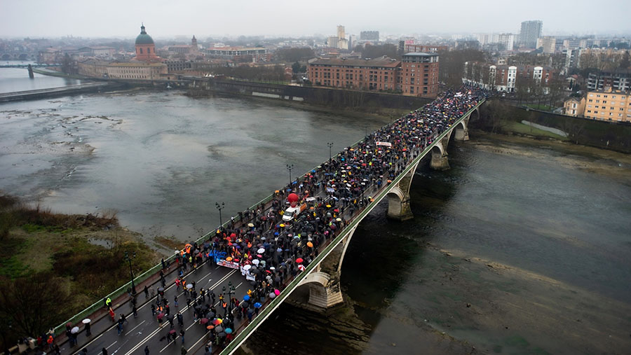 Demonstran menentang reformasi pensiun melintasi jembatan Pont des Catalans di Toulouse, Prancis, Selasa (7/3/2023). (Matthieu Rondel/Bloomberg)