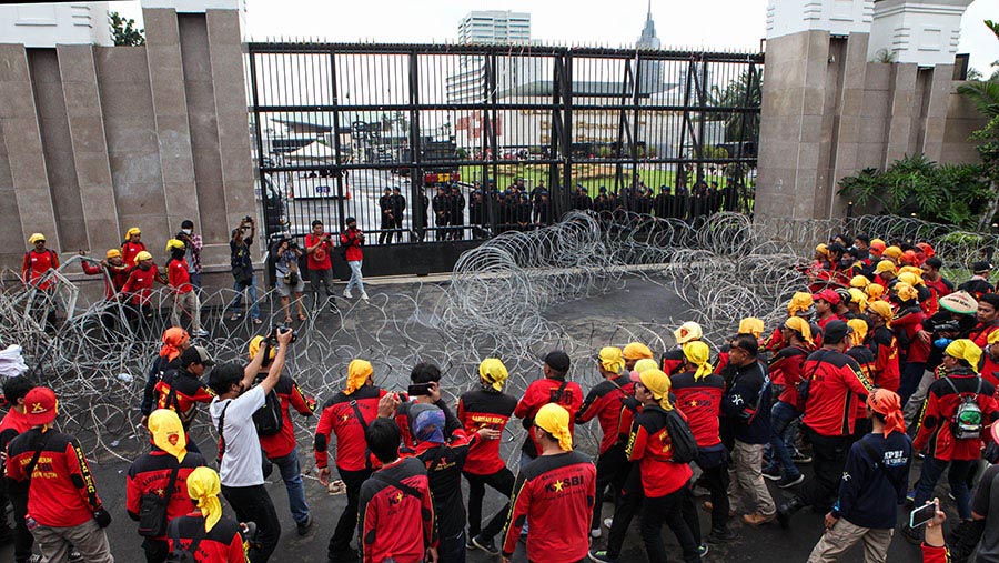 Massa buruh sempat menyingkirkan kawat berduri yang dipasang di depan gedung DPR/MPR RI. (Bloomberg Technoz/ Andrean Kristianto)