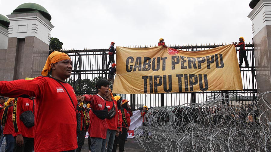 Usai menyingkirkan kawat berduri, massa buruh memasang spanduk di pagar gedung wakil rakyar tersebut (Bloomberg Technoz/ Andrean Kristianto)