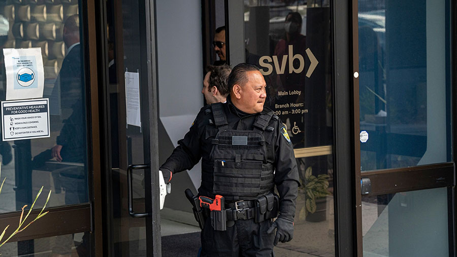 Penjaga keamanan di depan pintu kantor pusat Silicon Valley Bank (SVB) di Santa Clara, California, AS, Senin (13/3/2023) (David Paul Morris/Bloomberg)