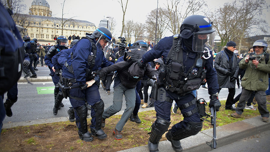 Polisi menahan pengunjuk rasa saat aksi mogok nasional menentang reformasi pensiun di Paris, Prancis, Rabu (15/3/2023). (Nathan Laine/Bloomberg)