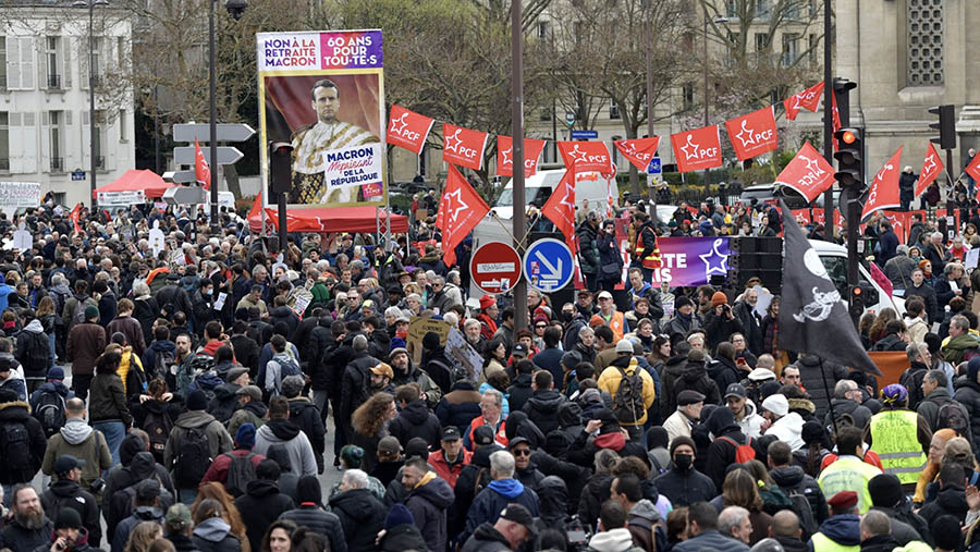 Spanduk anti-Macron dibawa saat aksi mogok nasional menentang reformasi pensiun di Paris, Prancis, Rabu (15/3/2023). (Nathan Laine/Bloomberg)