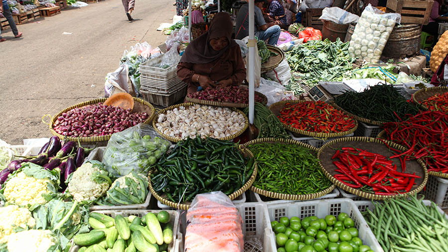 Pedagang mengupas bawang merah di Pasar Induk Kramat Jati, Jakarta, Kamis (16/3/2023). (Bloomberg Technoz/ Andrean Kristianto)