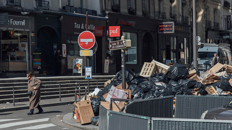 Pejalan kaki melewati kantong sampah yang menumpuk di Paris, Prancis, Selasa (21/3/2023). (Cyril Marcilhacy/Bloomberg)
