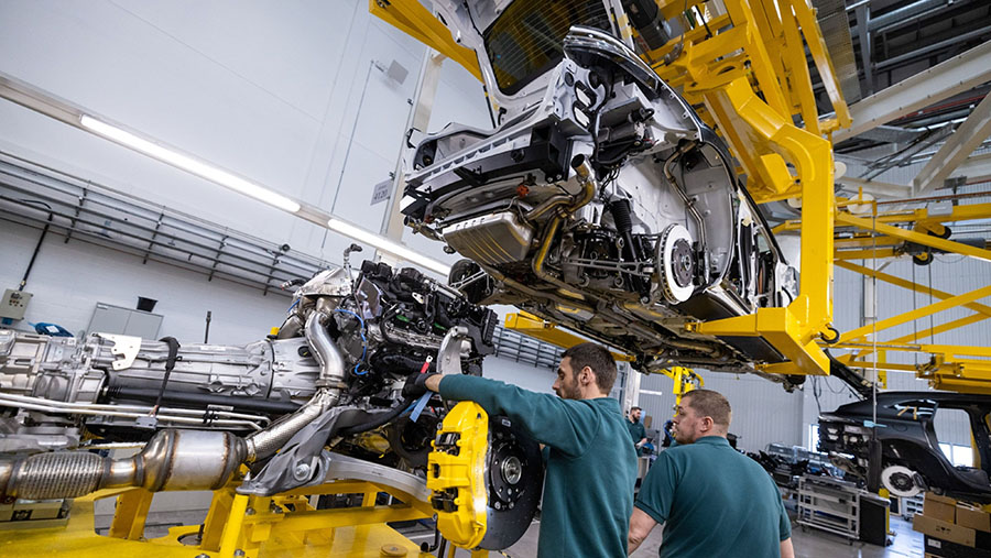 Karyawan memasang mesin dengan sasis SUV Aston Martin DBX di fasilitas manufaktur di St Athan, Inggris, Kamis (23/3/2023). (Chris Ratcliffe/Bloomberg)