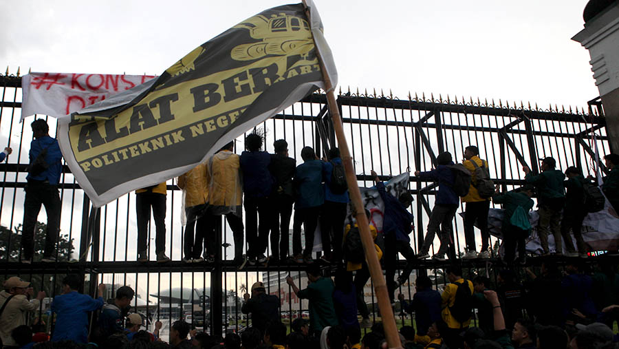 Para mahasiswa juga memanjat untuk merobohkan pagar gedung DPR/MPR.(Bloomberg Technoz/ Andrean Kristianto)