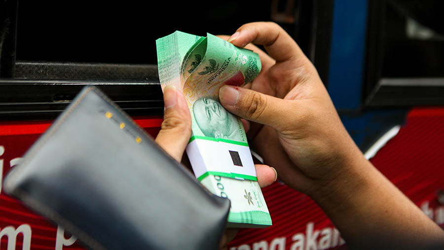 Warga menghitung uang rupiah di layanan kas keliling Bank Indonesia di Pasar Tebet, Selasa (4/4/2023). (Bloomberg Technoz/ Andrean Kristianto)