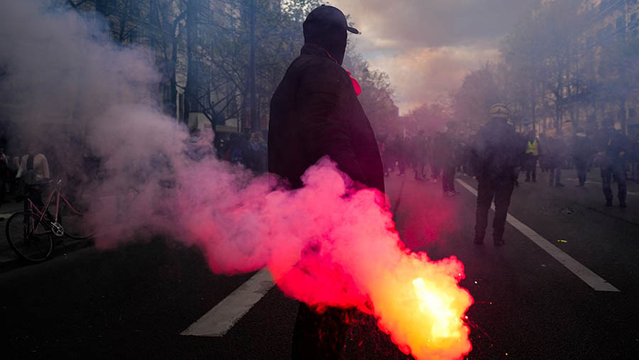 Pedemo memegang suar di Boulevard Raspail selama demo menentang reformasi pensiun  di Paris, Prancis, Kamis (6/4/2023).(Nathan Laine/Bloomberg)