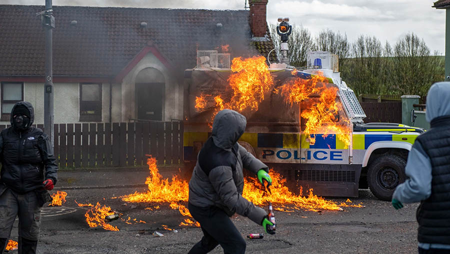 Massa melemparkan bom molotv ke kendaraan polisi di Londonderry, Irlandia Utara, Inggris, Senin (10/4/2023). (Chris J. Ratcliffe/Bloomberg)