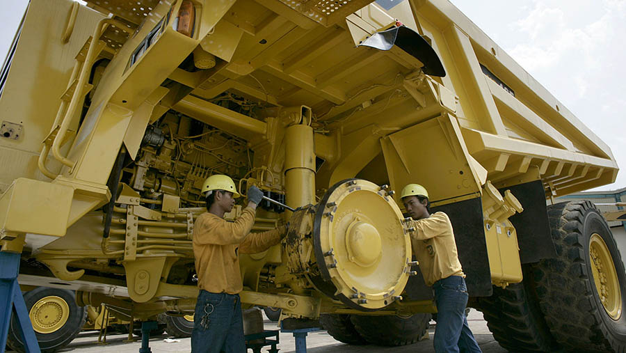 Pekerja PT United Tractors memeriksa wheel-well dump truck di Jakarta, Indonesia, Rabu (30/5/2023). (Dimas Ardian/Bloomberg)