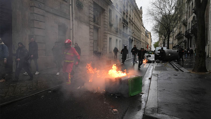 Tempat sampah dibakar oleh pendemo yang menentang hasil keputusan reformasi pensiun di Paris, Prancis, Jumat (14/4/2023). (Nathan Laine/Bloomberg)