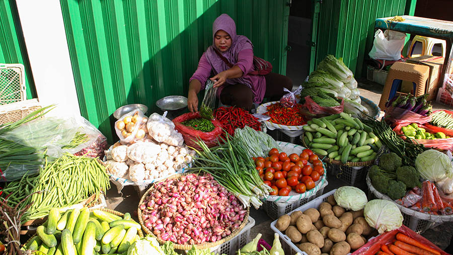 Pedagang melayani pembeli sayur di Pasar Minggu, Jakarta, Selasa (18/4/2023). (Bloomberg Technoz/ Andrean Kristianto)