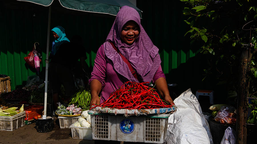 Pedagang memindahkan cabai keriting merah di Pasar Minggu, Jakarta, Selasa (18/4/2023). (Bloomberg Technoz/ Andrean Kristianto)