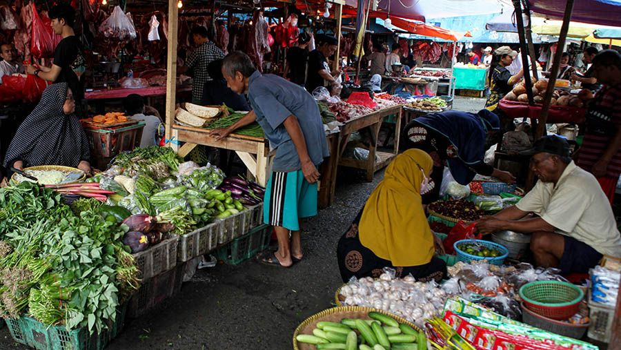 Pedagang melayani pembeli sayur di Pasar Minggu, Jakarta, Selasa (18/4/2023). (Bloomberg Technoz/ Andrean Kristianto)