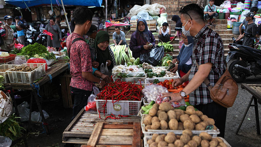 Pedagang melayani pembeli sayur dan cabai keriting merah di Pasar Minggu, Jakarta, Selasa (18/4/2023). (Bloomberg Technoz/ Andrean Kristianto)