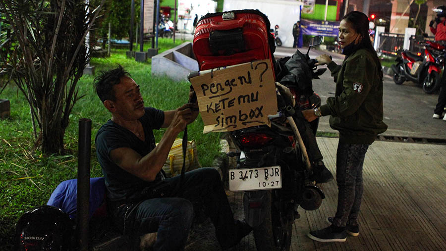 Pemudik sepeda motor merapihkan bareang bawaannya di kawasan Raya Kalimalang, Jawa Barat, Selasa (18/4/2023). (Bloomberg Technoz/ Andrean Kristianto)
