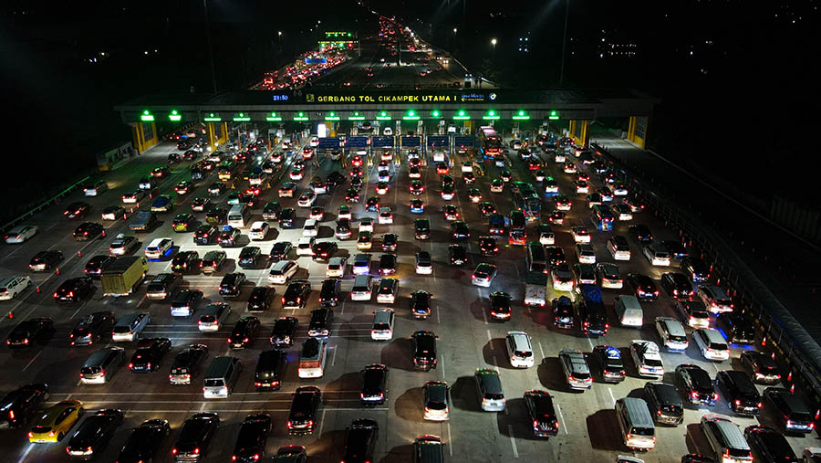 Suasana antrean kendaraan di Gerbang Tol Cikampek Utama 1, Jawa Barat, Rabu malam, (19/4/2023). (Bloomberg Technoz/ Andrean Kristianto)