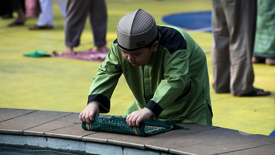 Anak melipat sajadah usai melaksanakan salat Idulfitri di Taman Menteng, Jakarta, Sabtu (23/4/2023). . (Bloomberg Technoz/ Andrean Kristianto)