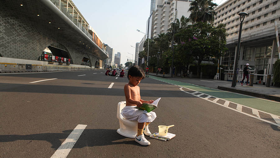 Tak hanya orang dewasa, anak kecilpun ikut berfoto saat jalanan Jakarta sepi. (Bloomberg Technoz/ Andrean Kristianto)