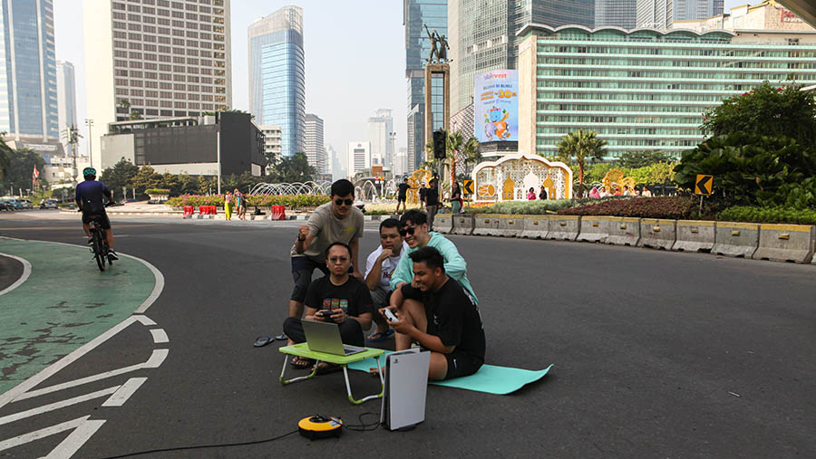 Warga befoto seolah-olah bermain gim saat jalanan sepi di kawasan Bundaran HI, Jakarta, Sabtu (22/4/2023). (Bloomberg Technoz/ Andrean Kristianto)