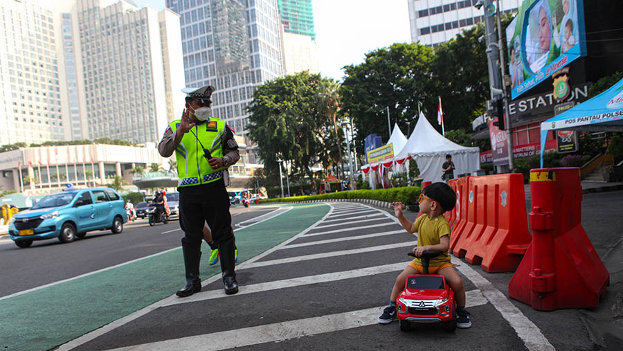 Polisi menyapa anak kecil yang bermain di kawasan Bundaran HI, Jakarta, Sabtu (22/4/2023). (Bloomberg Technoz/ Andrean Kristianto)