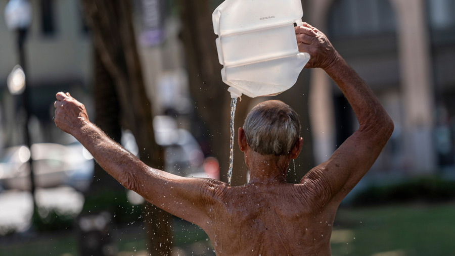 Seorang penduduk mendinginkan diri dengan sebotol air selama gelombang panas (David Paul Morris/Bloomberg)