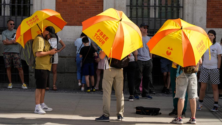 Pemandu wisata berlindung di bawah payung saat suhu tinggi di Madrid, Spanyol, pada Kamis, 27 April 2023. (Paul Hanna/Bloomberg)