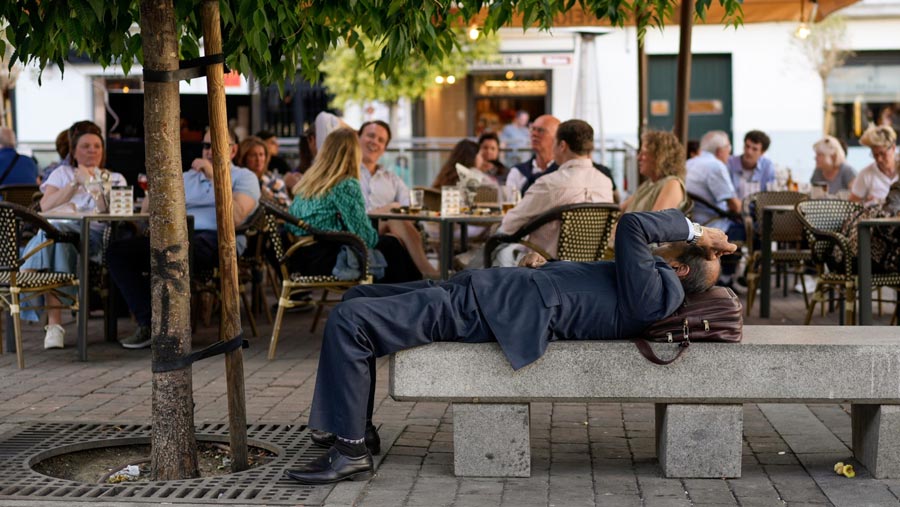 Seorang pekerja kantor beristirahat di tempat teduh di depan area teras kafe saat suhu tinggi di Spanyol (Paul Hanna/Bloomberg)