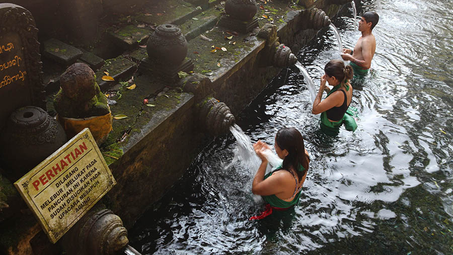 Turis asing melakukan ritual melukat di Pura Tirta Empul, Gianyar, Bali, Rabu (3/4/2023). (Bloomberg Technoz/ Andrean Kristianto)
