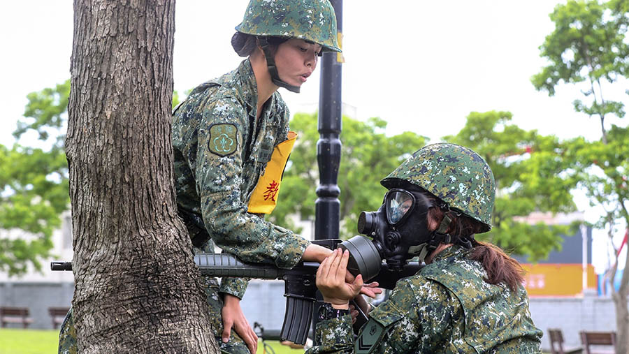 Para warnita tersebut mengikuti latihan militer lengkap dengan topeng gas dan senapan. (I-Hwa Cheng/Bloomberg)