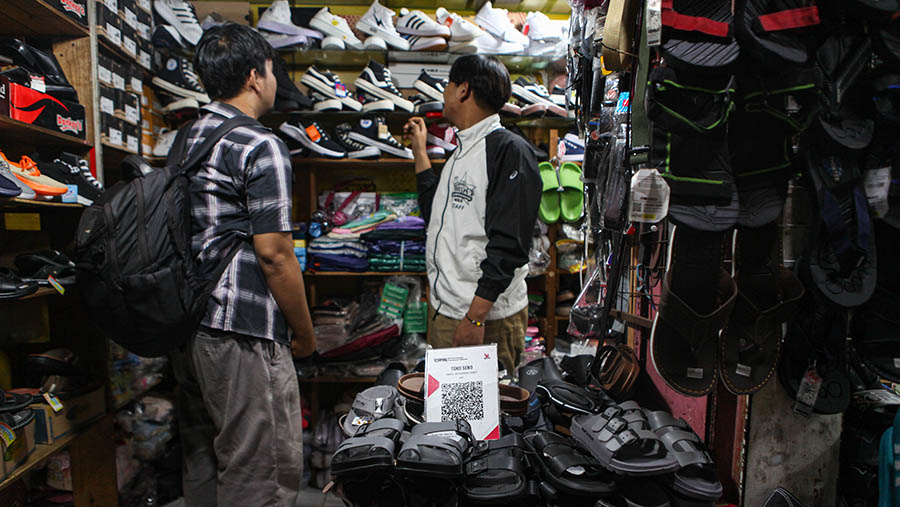 Kode batang (barcode) QRIS terpampang disalah satu kios penjualan sepatu di Pasar Minggu, Kamis (11/5/2023). (Bloomberg Technoz/ Andrean Kristianto)