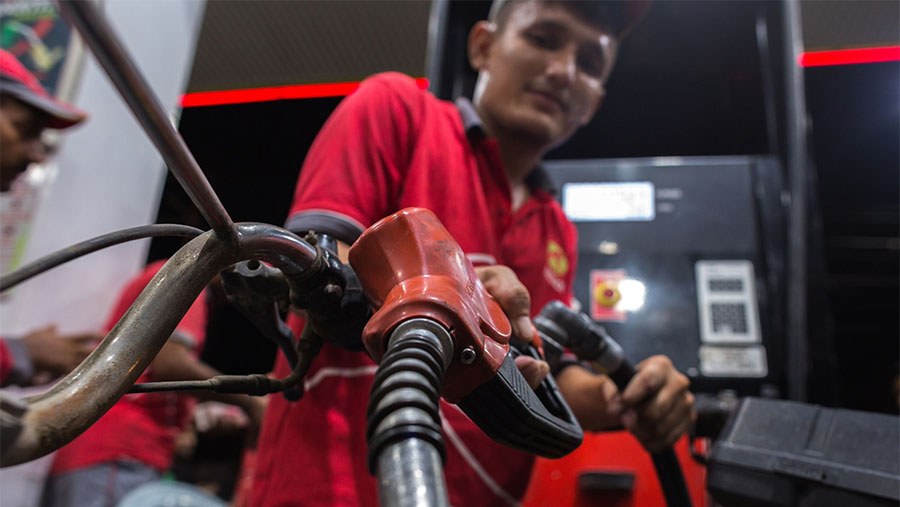 Seorang pekerja mengisi bahan bakar sepeda motor di sebuah pompa bensin. (Asim Hafeez/Bloomberg)