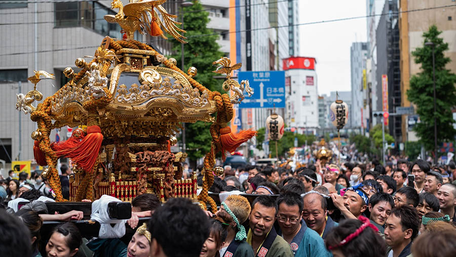 Dalam perayaannya, peserta dengan semangat tinggi mengusung replika kuil portabel yang berwarna emas di jalanan Tokyo. (Nicholas Takahashi/Bloomberg)