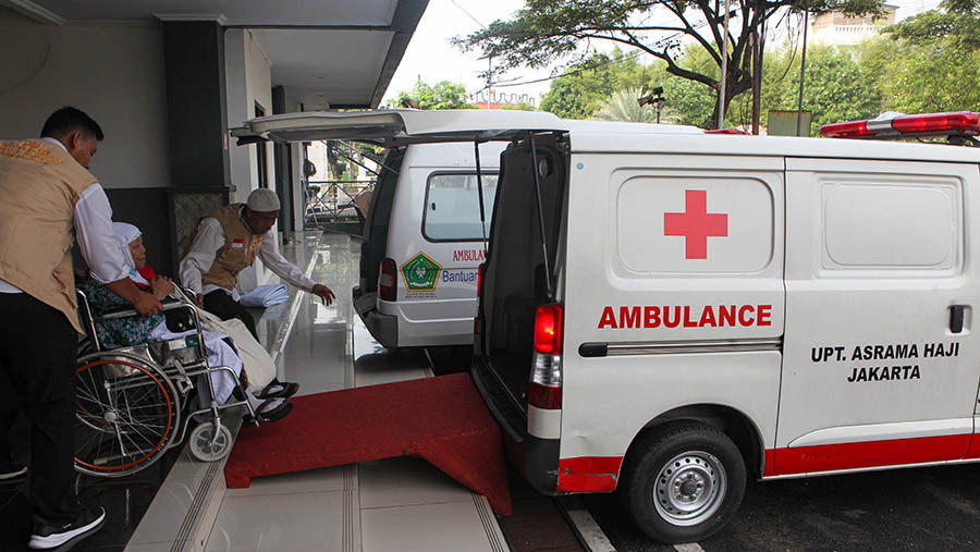 Petugas membantu calon jemaah haji lansia di Asrama Haji Pondok Gede, Jakarta, Selasa (23/5/2023). (Bloomberg Technoz/ Andrean Kristianto)