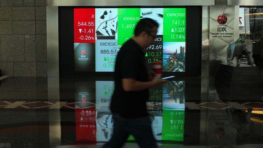 Karyawan melintas di dekat layar pergerakan Indeks Harga Saham Gabungan (IHSG) di Bursa Efek Indonesia (BEI). (Bloomberg Technoz/ Andrean Kristianto)