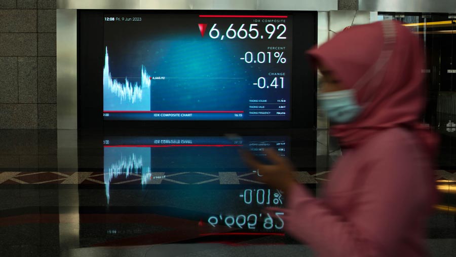 Karyawan melintas di dekat layar pergerakan Indeks Harga Saham Gabungan (IHSG) di Bursa Efek Indonesia (BEI). (Bloomberg Technoz/ Andrean Kristianto)