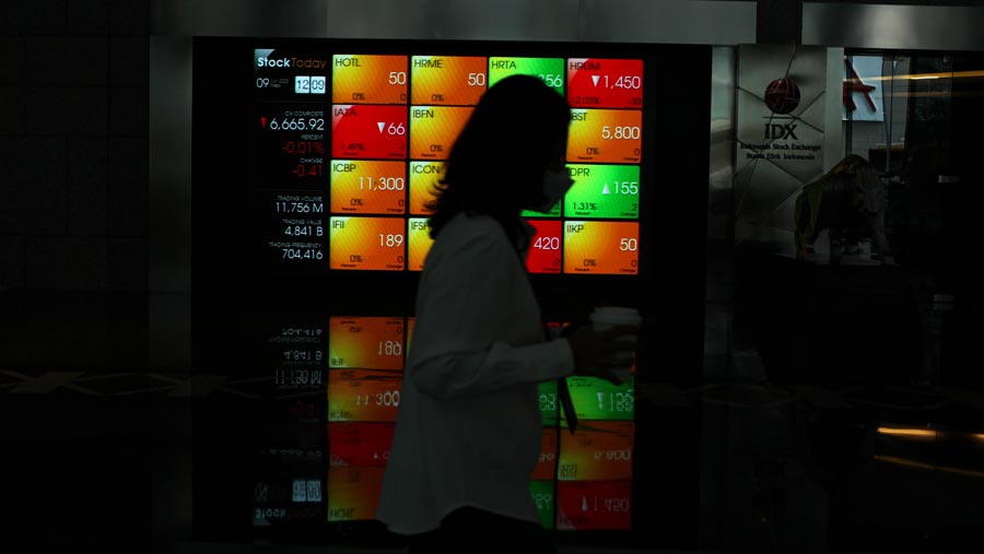 Karyawan melintas di dekat layar pergerakan Indeks Harga Saham Gabungan (IHSG) di Bursa Efek Indonesia (BEI). (Bloomberg Technoz/ Andrean Kristianto)